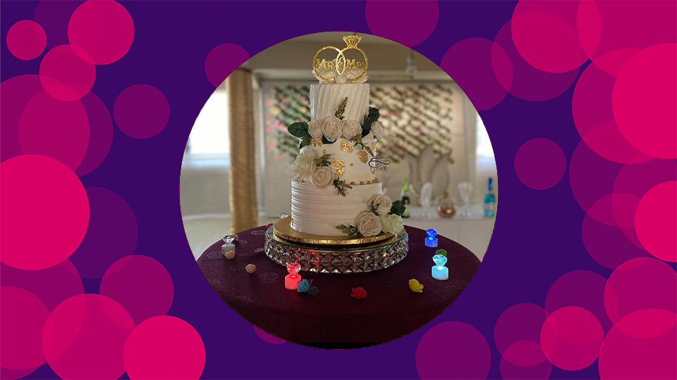 A purple background with pink circles on with an picture of an intricately designed wedding cake in the middle. 